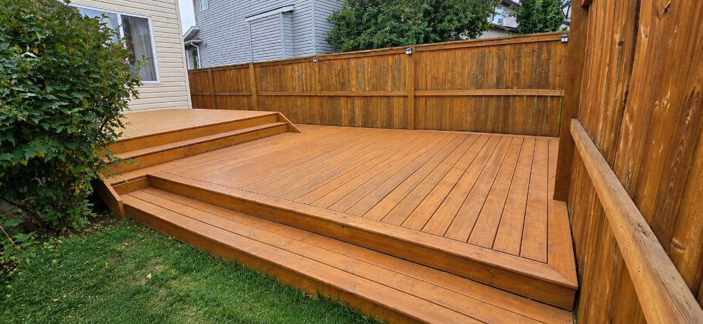 Stained wood deck with wide steps in a backyard
